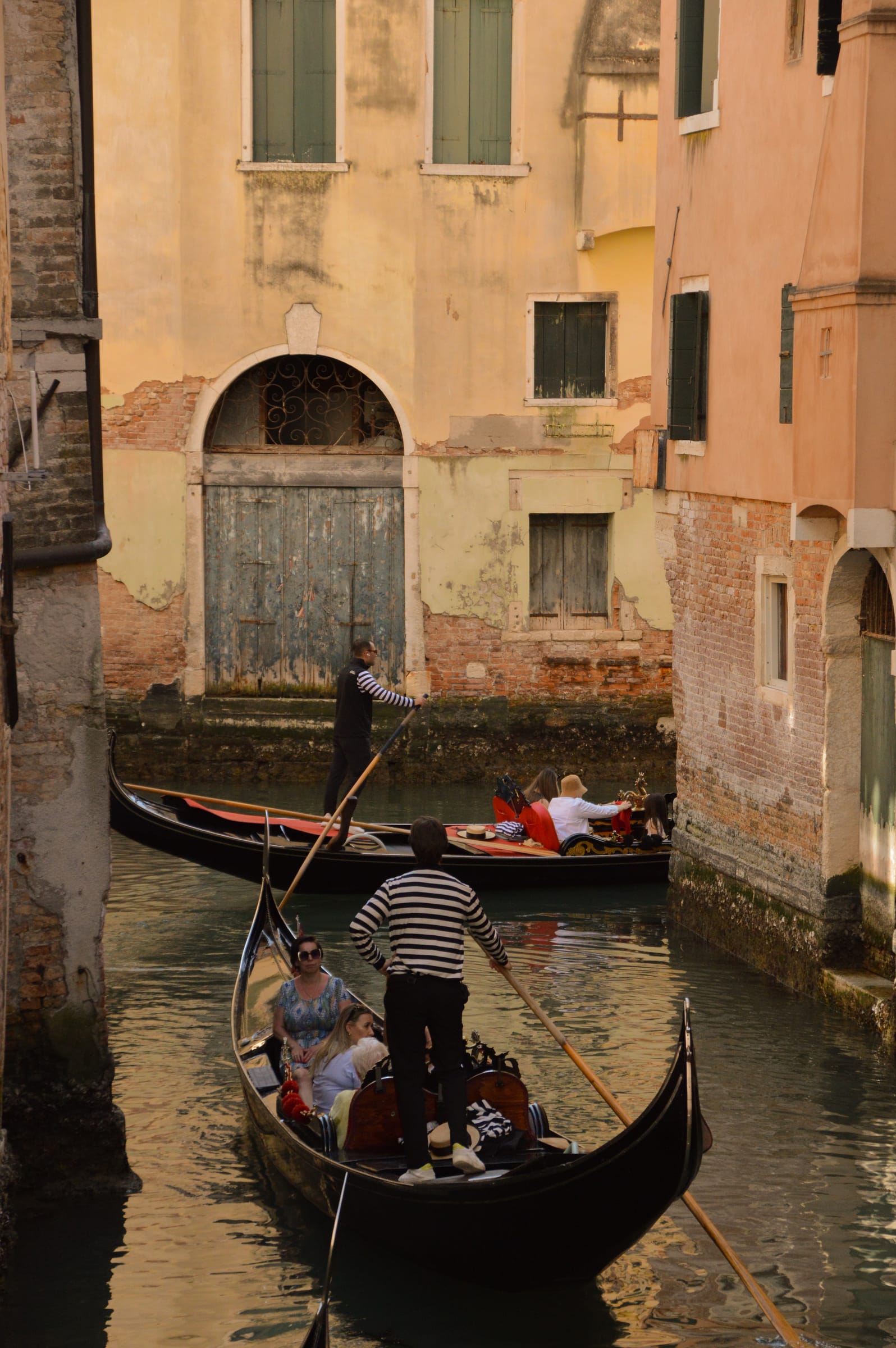 Gondoliers rowing along a Venice canal in warm evening light